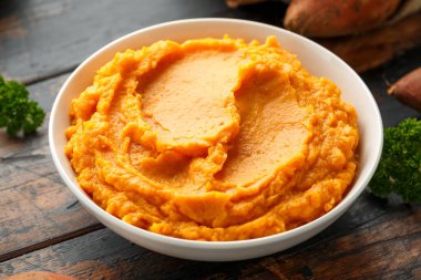 Tatlı patatesleri ahşap kırsal masada beyaz kasede ezdim. Sağlıklı yemek.