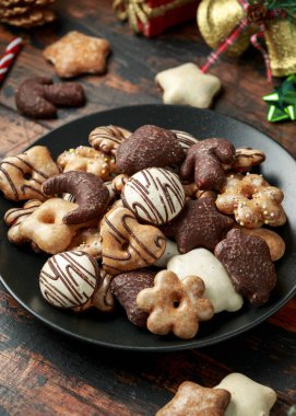 Noel zencefilli ekmek, süslemeli lebkuchen karışımı, hediyeler, ahşap kırsal masada yeşil ağaç dalı.