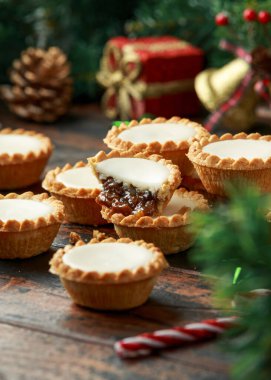 İngiliz Noel 'i süslenmiş, hediyeli buzlu turtalar, ahşap kırsal masada yeşil ağaç dalı.