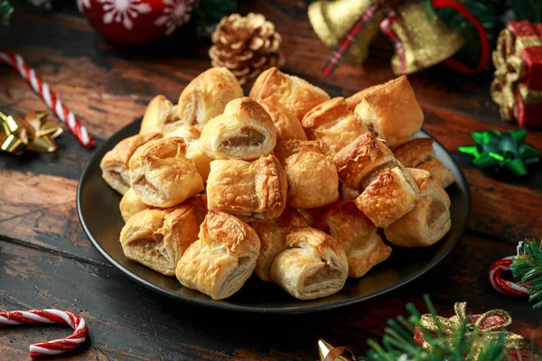 Rollos de salchicha de Navidad con decoración, regalos, rama de árbol verde en mesa rústica de madera —  Fotos de Stock