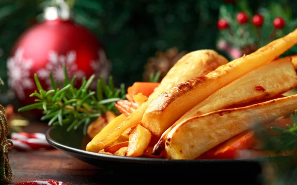 Panais et carottes rôtis de Noël avec décoration, cadeaux, branche d'arbre vert sur table rustique en bois — Photo