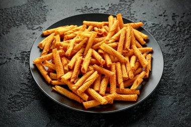 Çedar peynirli tortilla rulosu, siyah tabakta cips.
