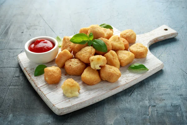 Gebratener Mozzarella, Cheddar-Käsehäppchen, Bällchen mit Ketchup auf weißem Holzbrett — Stockfoto