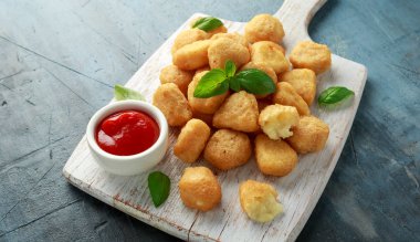 Kızarmış mozzarella, çedar peyniri ısırıkları, beyaz tahta üzerinde ketçaplı toplar.