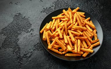 Çedar peynirli tortilla rulosu, siyah tabakta cips.