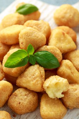 Kızarmış mozzarella, çedar peyniri ısırıkları, beyaz tahta üzerinde ketçaplı toplar.