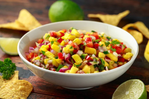 Bowl of fresh Mango Salsa with nachos chips and herbs. Healthy Vegan, Vegetables food.
