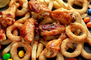Sağlıksız, fast food konsepti. Soğan halkaları, pizza, patates kızartması, bbq tavuğu, şeker, çikolata, patates cipsi, tuzlu fıstık..