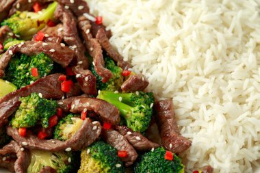 Ev yapımı biftek ve brokoli, pirinç ve ahşap masada otlar.