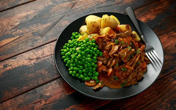 Klassisk nötkött stroganoff servei med kokt baby potatis och söta ärtor — Stockfoto