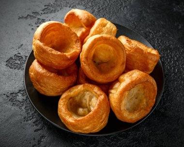 Geleneksel İngiliz Yorkshire pudingi siyah tabak ve arkaplan üzerine