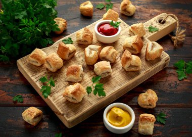 Ahşap tahtada hardal ve ketçap soslu domuz sucuğu rulosu.