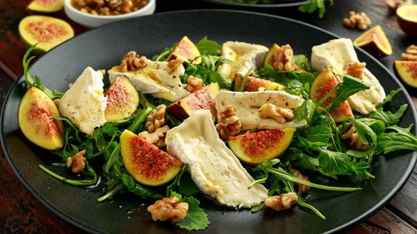 Вегетарианский сыр камамбер, инжир и аругула, салат с горячей ракетой на черной тарелке — стоковое фото