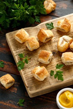 Ahşap tahtada hardal ve ketçap soslu domuz sucuğu rulosu.