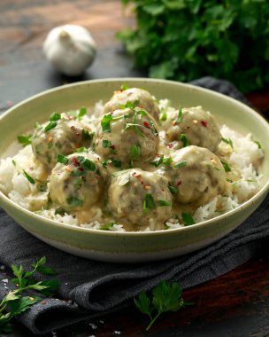 Beyaz pirinç ve ahşap masada kızılcık soslu sıcak İsveç köftesi.