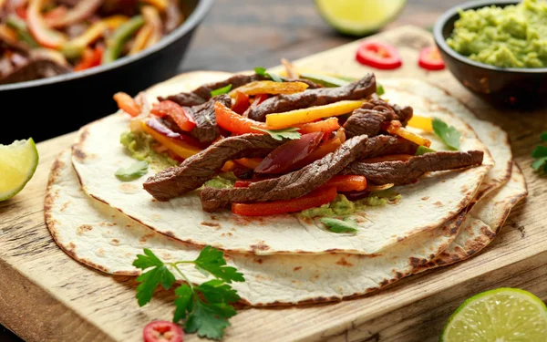 Bife de Carne Fajitas com tortilla misturar pimenta, cebola e abacate em tábua de madeira — Fotografia de Stock