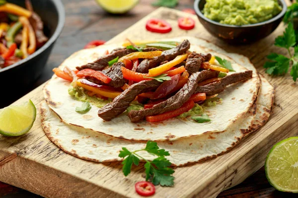 Bife de Carne Fajitas com tortilla misturar pimenta, cebola e abacate em tábua de madeira — Fotografia de Stock