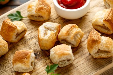 Ahşap tahtada hardal ve ketçap soslu domuz sucuğu rulosu.