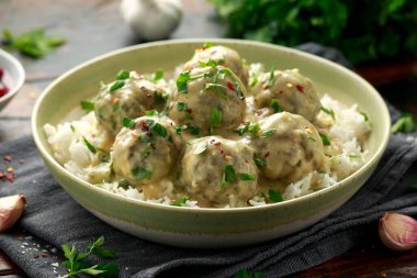 Beyaz pirinç ve ahşap masada kızılcık soslu sıcak İsveç köftesi.