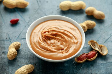 Smooth Peanut Butter in white bowl with nuts