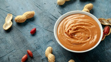 Smooth Peanut Butter in white bowl with nuts