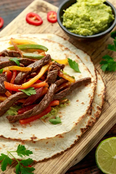 Bife de Carne Fajitas com tortilla misturar pimenta, cebola e abacate em tábua de madeira — Fotografia de Stock