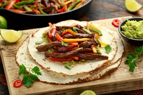 Bife de Carne Fajitas com tortilla misturar pimenta, cebola e abacate em tábua de madeira — Fotografia de Stock