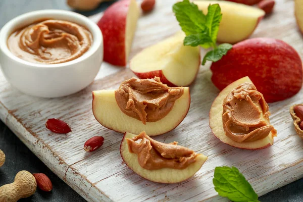 Peanut butter and apple to snack. on white wooden board