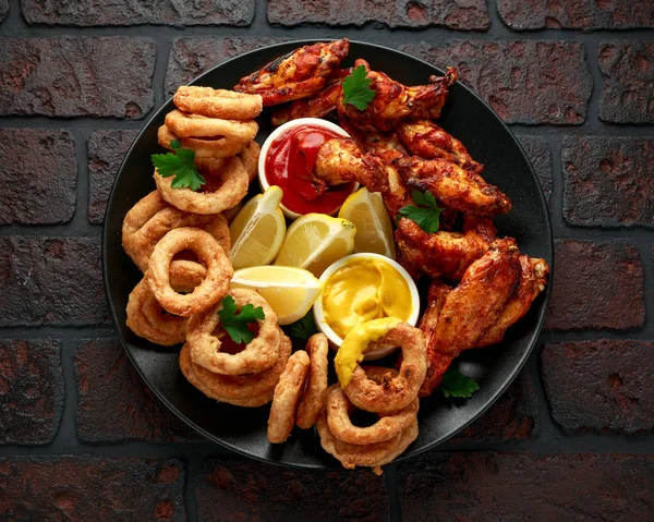 Sticky glazed chicken wings and deep fried battered onion rings served with lemon wedges, tomato ketchup and mustard. Greasy, fast food concept
