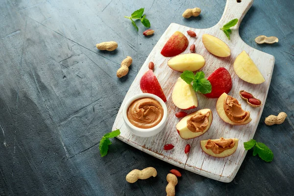 Peanut butter and apple to snack. on white wooden board