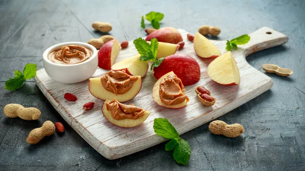 Peanut butter and apple to snack. on white wooden board