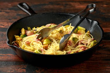 Ev yapımı Brüksel lahanası, pastırma, parmesan peynirli pancetta makarna. Tahta masada.