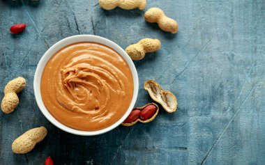 Smooth Peanut Butter in white bowl with nuts