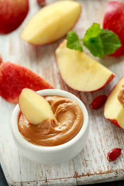 Peanut butter and apple to snack. on white wooden board