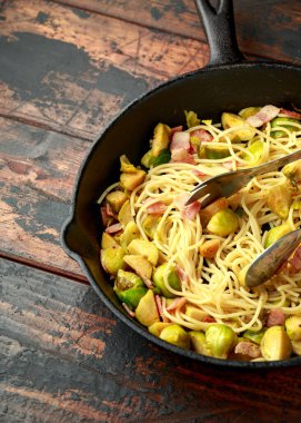 Ev yapımı Brüksel lahanası, pastırma, parmesan peynirli pancetta makarna. Tahta masada.