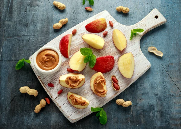 Peanut butter and apple to snack. on white wooden board