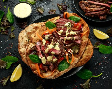 Izgara ve dilimlenmiş biftek sarımsaklı ve kişniş ekmekli havuçlu ve ev yapımı mayonez soslu ıspanak salatası..