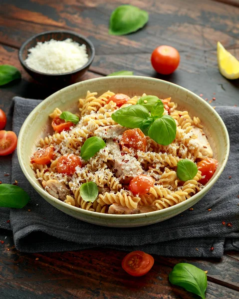 Gezonde kip, fusilli pasta met tomaten, basilicum en parmezaanse kaas. op houten tafel. — Stockfoto