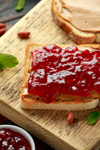 Erdnussbutter und Erdbeergelee-Sandwich auf Holzbrett. Frühstück am Morgen — Stockfoto