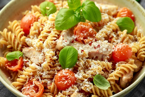 Gezonde kip, fusilli pasta met tomaten, basilicum en parmezaanse kaas. op houten tafel. — Stockfoto