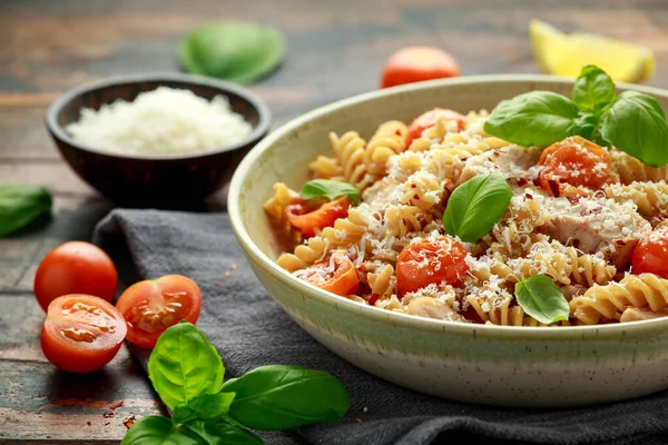 Gezonde kip, fusilli pasta met tomaten, basilicum en parmezaanse kaas. op houten tafel. — Stockfoto