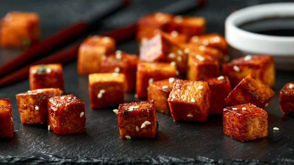 Tofu frito com pauzinho e sementes de gergelim em tábua de pedra rústica — Fotografia de Stock