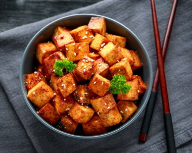 Çubuk ve susamlı kase içinde kızarmış tofu.