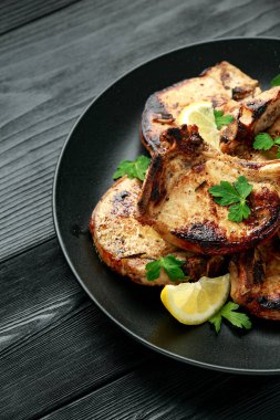 Ev yapımı ızgara domuz filetosu ve limon soslu pirzola. Kırsal ahşap masa üzerinde otlar.