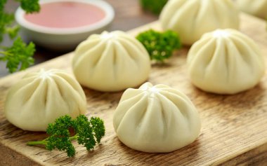 Ördek dolması ile buharda pişmiş çörek, ahşap tahtada kırmızı biber sosu. Asya yemekleri.