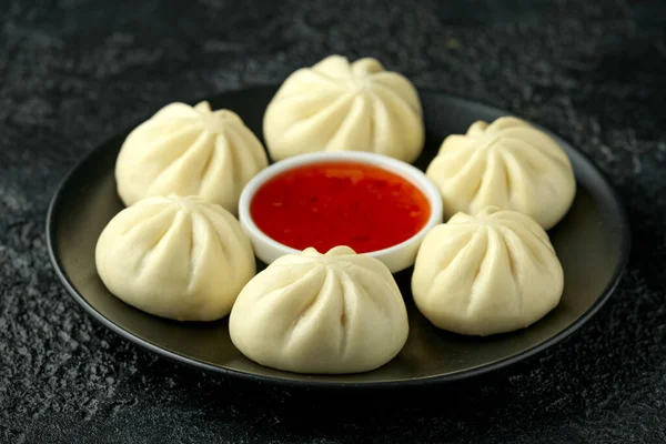 Steamed Buns with duck stuffing, chili sauce on black plate