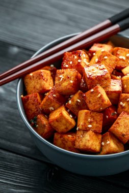 Çubuk ve susamlı kase içinde kızarmış tofu.