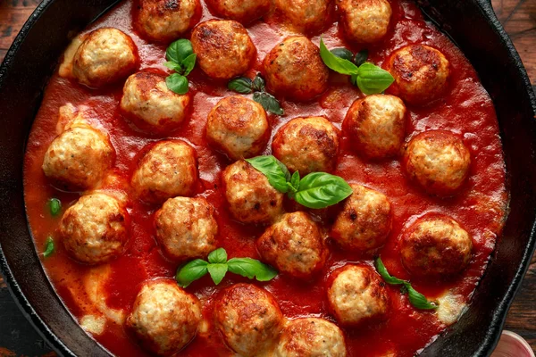 Lean Turkey breast meat balls in cheesy tomato passata sauce served in cast iron frying pan skillet