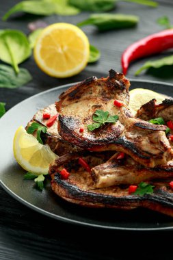 Ev yapımı ızgara domuz filetosu ve limon soslu pirzola. Kırsal ahşap masa üzerinde otlar.