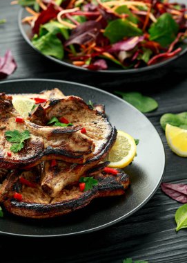 Ev yapımı ızgara domuz filetosu ve limon soslu pirzola. Kırsal ahşap masa üzerinde otlar.